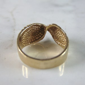 May include: A gold-toned ring with a twisted design. The ring is smooth and shiny.