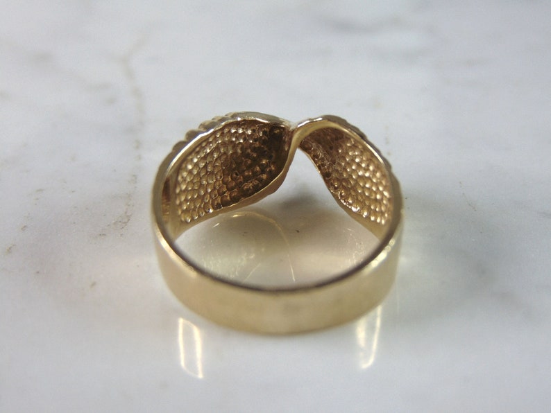 May include: A gold-toned ring with a twisted design. The ring is smooth and shiny.