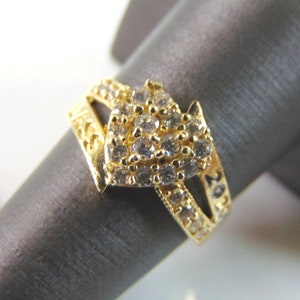 May include: A gold ring with a heart-shaped design set with clear cubic zirconia stones.