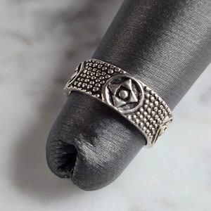 May include: A silver ring with a textured band and a star-shaped design.