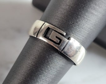 May include: Silver ring with a geometric design featuring the letter G.