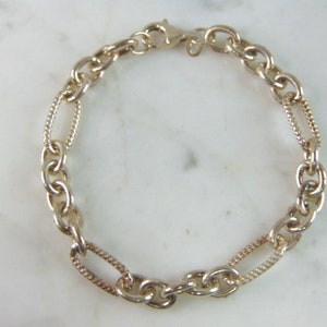 May include: A silver chain bracelet with two different link styles. The bracelet has a lobster claw clasp.