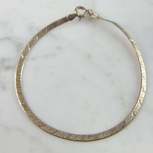 May include: A silver, textured, hoop earring with a simple clasp.