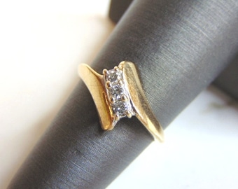 May include: A gold ring with a row of small diamonds set in a diagonal line.