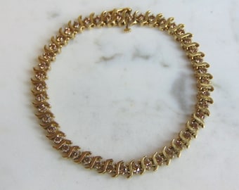 May include: A gold chain necklace with small clear stones set in a zig-zag pattern.