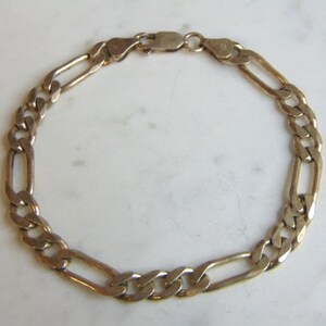 May include: A gold chain bracelet with a figaro link pattern.