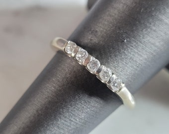 Op de afbeelding: Een zilveren band met een rij kleine, heldere diamanten in een gebogen ontwerp.
