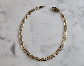 May include: A gold chain bracelet with a mariner link design. The bracelet is made of a shiny metal and has a clasp closure.