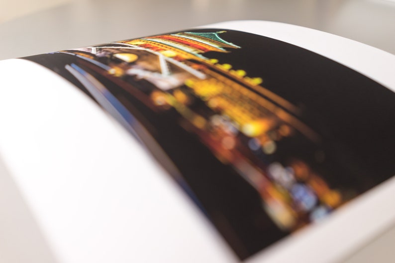 May include: A photograph of a building at night, with a focus on the colorful lights and architectural details. The image is slightly blurred, creating a soft, dreamlike effect. The photograph is on a white page.