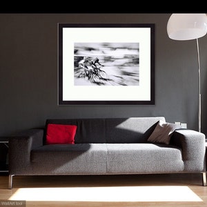 May include: Black and white framed print of cyclists in motion, displayed above a gray sofa with a red pillow. The room features a modern design with a floor lamp and a gallery wall of framed photos.