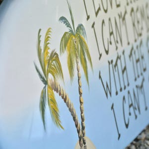 May include: Oval wooden sign with a light blue and white background, featuring two palm trees and the text "I LOVE THE MEMORIES I CAN'T REMEMBER WITH THE FRIENDS I CAN'T FORGET".