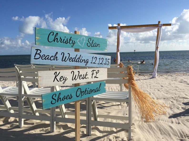 Beach wedding directional sign wood boards with bride and groom names, wedding date and shoes optional painted on beach colored theme, with a wedding wood arch in the back