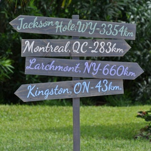 wood stained direction sign post with mileage, destination arrows signage, weathered grey