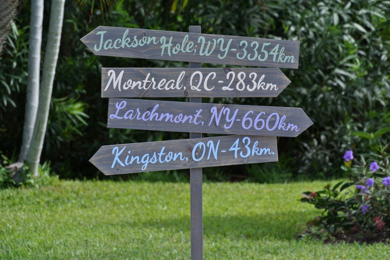 wood stained direction sign post with mileage, destination arrows signage, weathered grey