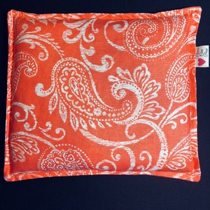 May include: An orange rectangular pillow with a white paisley pattern. The pillow has a white border and a tag that says "Mom's Care Bags" with a heart. The pillow is on a dark blue surface.