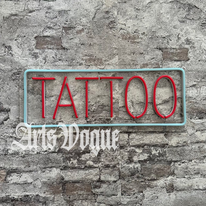 May include: A blue and white neon sign with the word "TATTOO" in red neon letters against a brick wall background.