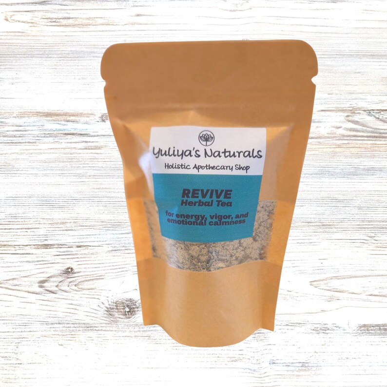 May include: A brown paper pouch with a clear window showing a blend of dried herbs. The pouch has a label that reads "Yuliya's Naturals Holistic Apothecary Shop REVIVE Herbal Tea for energy, vigor, and emotional calmness."