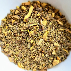May include: A close-up of a bowl filled with a blend of dried herbs and spices, including licorice root, thyme, and other herbs.
