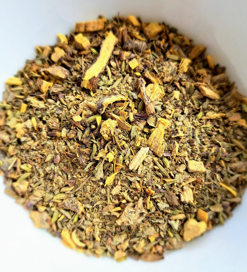 May include: A close-up of a bowl filled with a blend of dried herbs and spices, including licorice root, thyme, and other herbs.