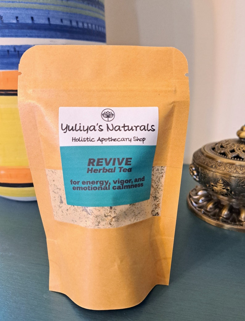 May include: A brown paper pouch with a label that reads "Yuliya's Naturals Holistic Apothecary Shop REVIVE Herbal Tea for energy, vigor, and emotional calmness".