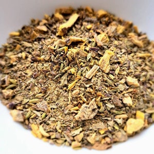 May include: A close-up of a blend of dried herbs and spices, including licorice root, for making tea. The mixture is a mix of brown, yellow, and green hues.