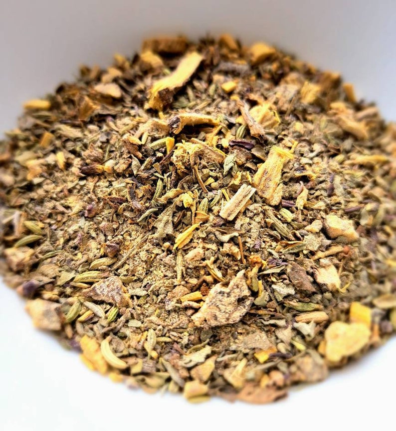 May include: A close-up of a blend of dried herbs and spices, including licorice root, for making tea. The mixture is a mix of brown, yellow, and green hues.