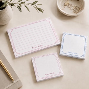 May include: Three rectangular and square paper notepads with decorative borders. One large lined notepad features the name Rose Vega in pink. Two smaller square notepads feature the names Alana Harris in pink and Lilliana Evers in blue ink.