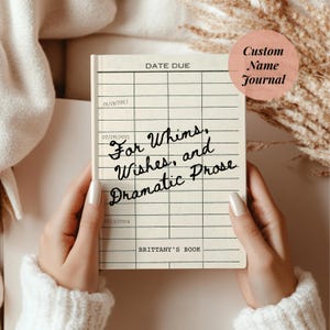 May include: A custom journal with a vintage library card design. The cover features the text "For Whims, Wishes, and Dramatic Prose" and "Brittany's Book." A pink circle reads "Custom Name Journal."