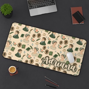 Puede incluir: Alfombrilla de escritorio rectangular beige con un patrón repetido de ilustraciones vintage, que incluyen retratos, libros y elementos florales. El nombre "Adriana" está escrito en cursiva. Un ratón de ordenador descansa sobre la alfombrilla.