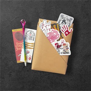 May include: A brown paper envelope filled with true crime themed stickers. The stickers feature various designs, including a bloody handprint, a fingerprint, a person with blood splatters, and the text "Fueled by Coffee & True Crime".