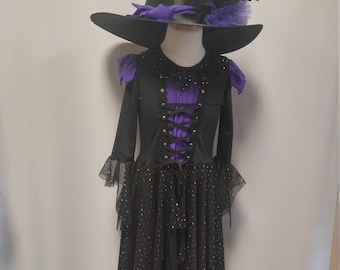 May include: A black witch costume with a purple bodice and a black skirt with silver glitter. The costume includes a black witch hat with a purple ribbon and a black feather.