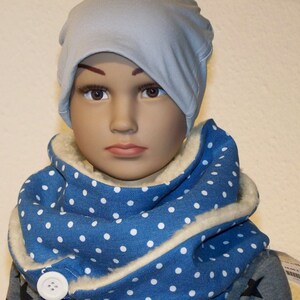 Puede incluir: Una bufanda azul y blanca con lunares, con forro de lana blanca y un bot&oacute;n blanco. La bufanda la lleva un ni&ntilde;o que lleva una boina azul claro.