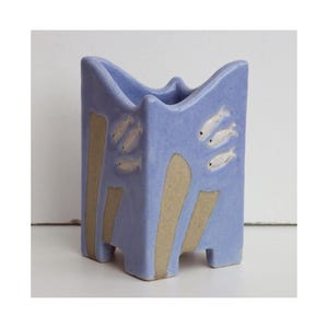 May include: A white ceramic mug with a black handle and the text "But first, coffee" in a handwritten style. The mug is on a white surface. The mug is 10 cm tall.