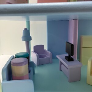 May include: A miniature dollhouse interior with pastel-colored furniture. The scene includes a sofa, armchair, table with a TV, and a lamp. The color palette features shades of blue, purple, and pink, creating a soft and inviting atmosphere.