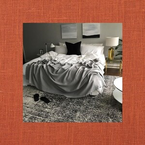May include: A gray throw blanket draped over a white bed with white pillows and a black throw pillow. The bed is in a bedroom with a gray wall and two abstract paintings on the wall.