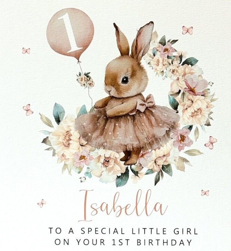 May include: A watercolour illustration of a bunny wearing a tutu and holding a balloon with the number 1. The bunny is surrounded by a floral wreath and butterflies. The text reads "Isabella, To a special little girl on your 1st birthday."