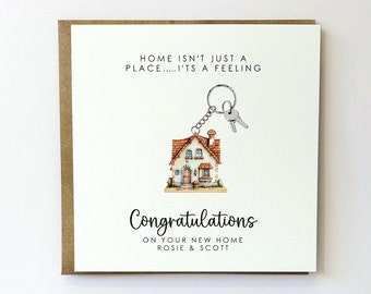 May include: A white card with a brown envelope. The card has a house key charm with a small house illustration and the text "HOME ISN'T JUST A PLACE..... IT'S A FEELING". The card also has the text "Congratulations ON YOUR NEW HOME ROSIE & SCOTT".