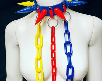 May include: A blue, red, and yellow spiked collar with three matching chains hanging from it. The chains are made of plastic and are linked together.
