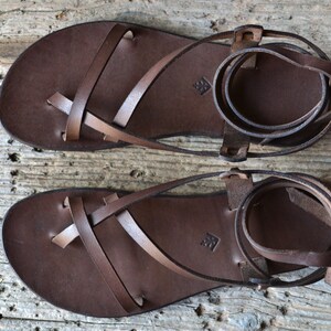 May include: A pair of brown leather sandals with criss-cross straps and ankle ties.