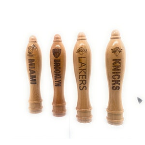 May include: Four wooden beer tap handles with NBA team logos. The handles are engraved with the team names: Miami Heat, Brooklyn Nets, Los Angeles Lakers, and New York Knicks.
