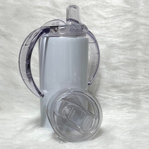 May include: White stainless steel tumbler with a clear lid and two handles. The lid has a straw opening and a clear silicone spout.