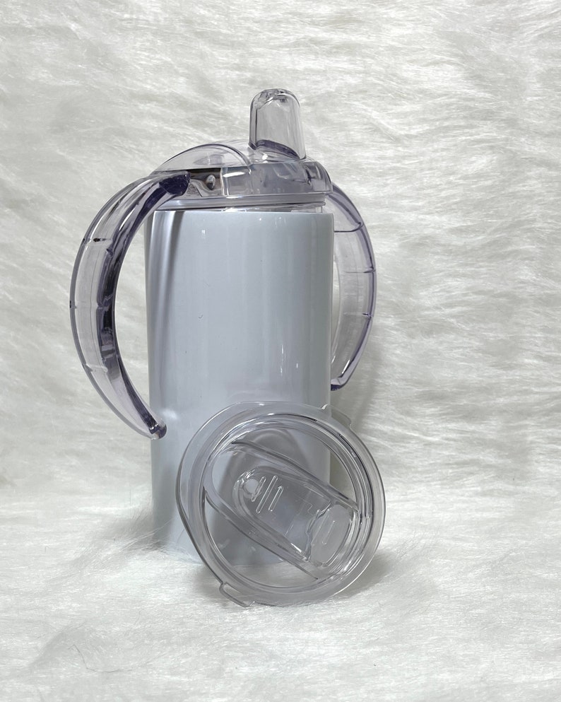 May include: White stainless steel tumbler with a clear lid and two handles. The lid has a straw opening and a clear silicone spout.