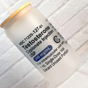 May include: A frosted glass bottle with a bamboo lid and a clear straw. The bottle has text that reads "Testosterone Cypionate Injection USP 200 mg/mL". The bottle is for intramuscular use only.