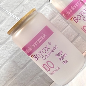 May include: A frosted glass jar with a bamboo lid and a straw. The jar is labeled "BOTOX® Cosmetic" and "100 Units/vial Single Patient Use".