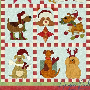 May include: A patchwork quilt with a Christmas theme featuring dogs wearing Santa hats and holding presents. The quilt is made of red, green and white fabric and has a chequered pattern. The quilt is signed "Angie Padilla".