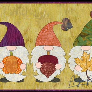 Könnte beinhalten: Drei Gnome mit weißen Bärten und verschiedenen farbigen Hüten halten herbstliche Gegenstände. Der Gnome links hält einen Kürbis, der mittlere Gnome hält eine Eichel und der Gnome rechts hält ein Blatt. Die Gnome stehen auf einem gelben Hintergrund mit einer Unterschrift unten.
