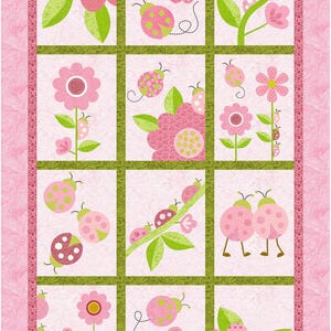 以下が含まれることがあります： ピンクとグリーンのパッチワークキルトで、テントウムシと花が繰り返しパターンになっています。キルトはピンクの縁取りで囲まれており、右下隅に「Angie Padilla」というテキストがあります。