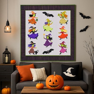 Puede incluir: Un edredón con temática de Halloween con brujas caprichosas con vestidos y sombreros coloridos, con murciélagos. El edredón está enmarcado en un borde morado oscuro y cuelga sobre un sofá gris decorado con almohadas naranjas, calabazas y una linterna.