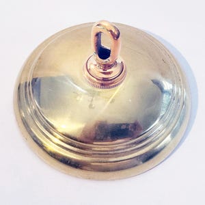 以下が含まれることがあります： 装飾的なリングと照明器具を吊るすためのフックが付いた、金色の金属製の天井キャノピーです。