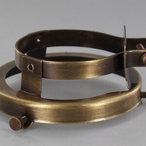 Puede incluir: Un anillo de pantalla de l&aacute;mpara de lat&oacute;n con dos tornillos en el lateral y uno en la parte inferior.